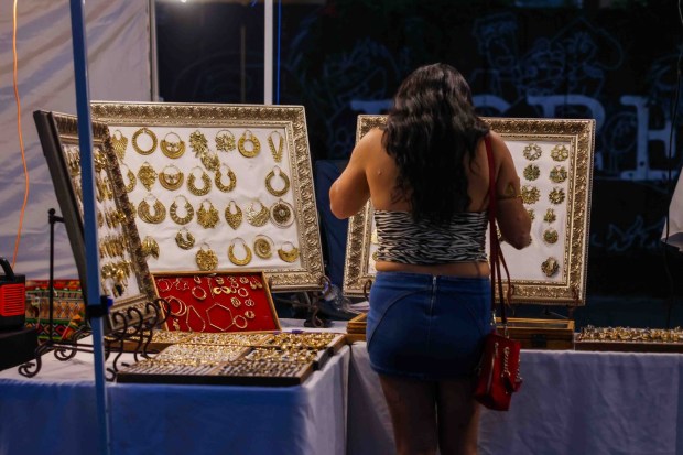 A festivalgoer looks at jewelry in a vendor's booth during the Oakland First Fridays event along Telegraph Avenue in Oakland, Calif., Friday, April 3, 2026. (Ray Chavez/Bay Area News Group)