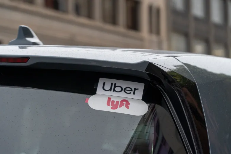 close-up photo of the back windshield of a car with Uber and Lyft signs
