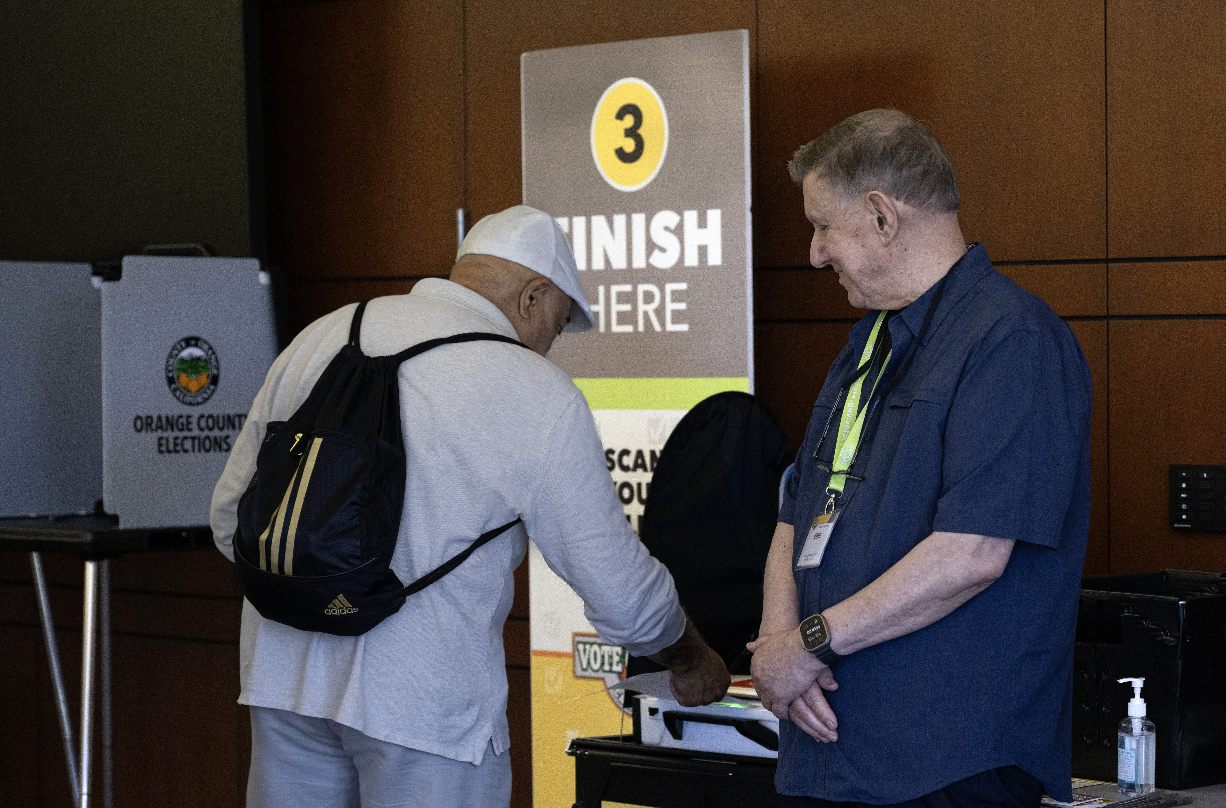 A poll worker helps a man finish the voting process...