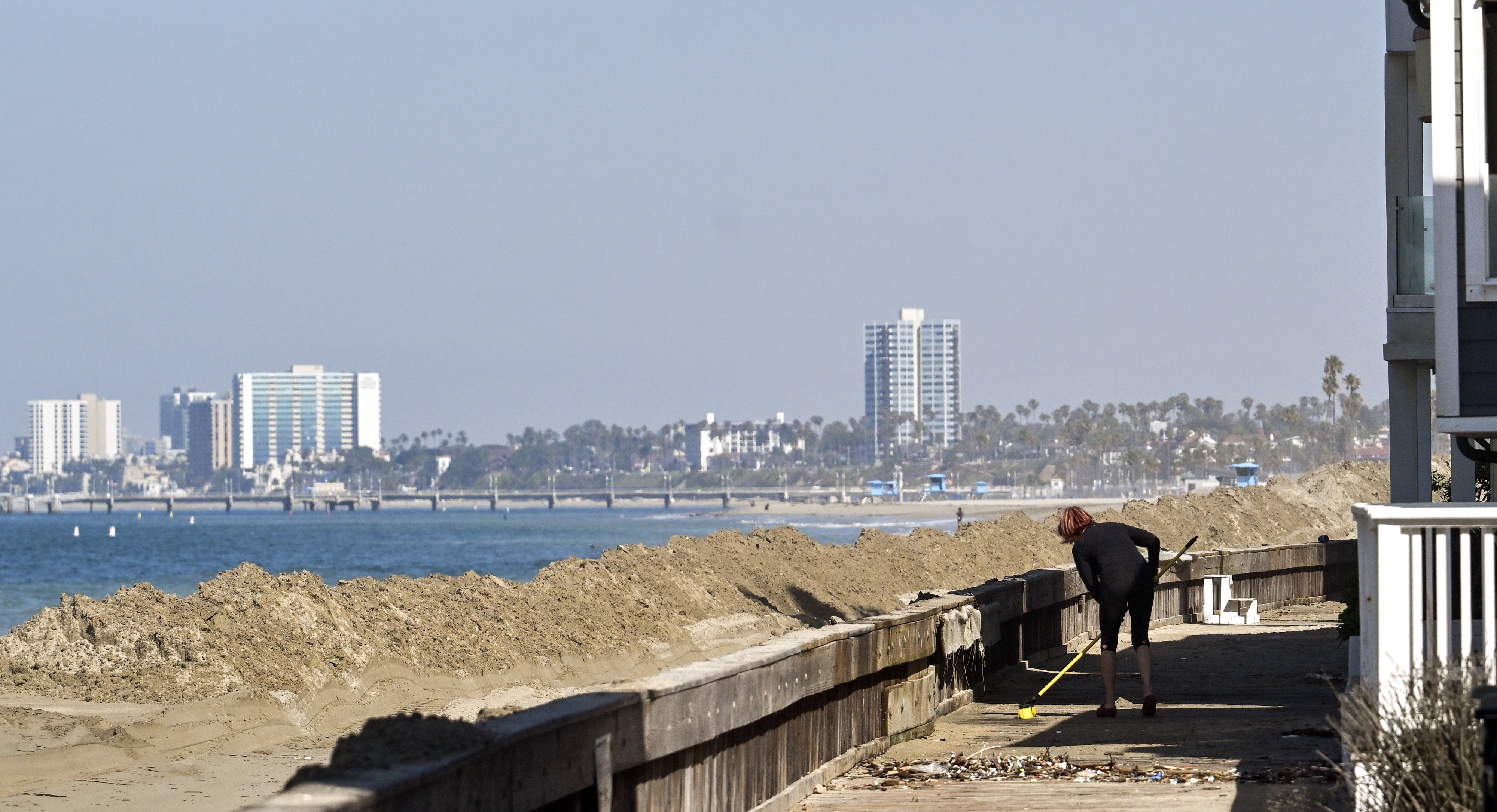 Gabriella Holt cleans up sand along the boardwalk in front...