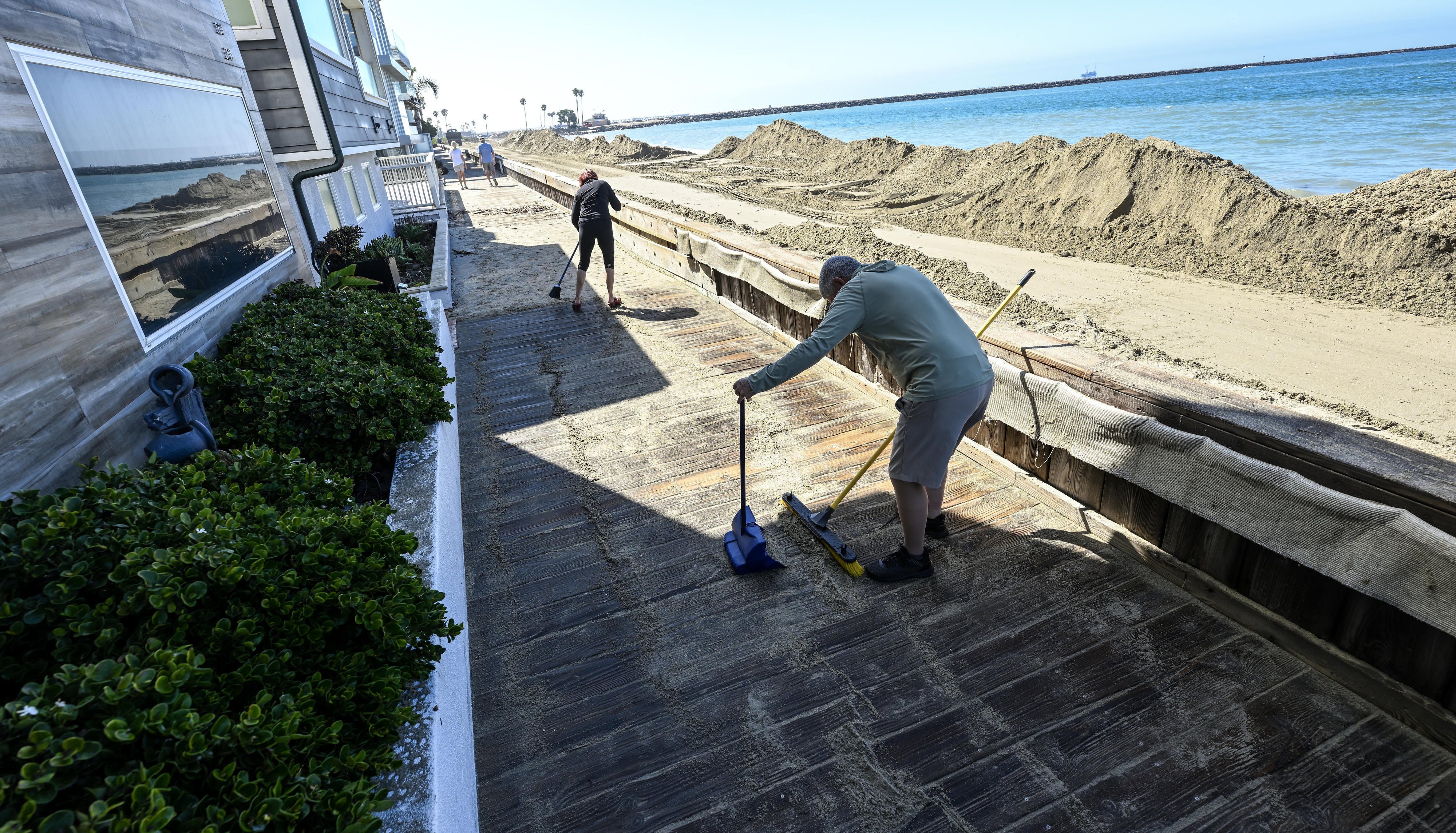 Ken Holt, and his wife, Gabriella Holt, clean up sand...