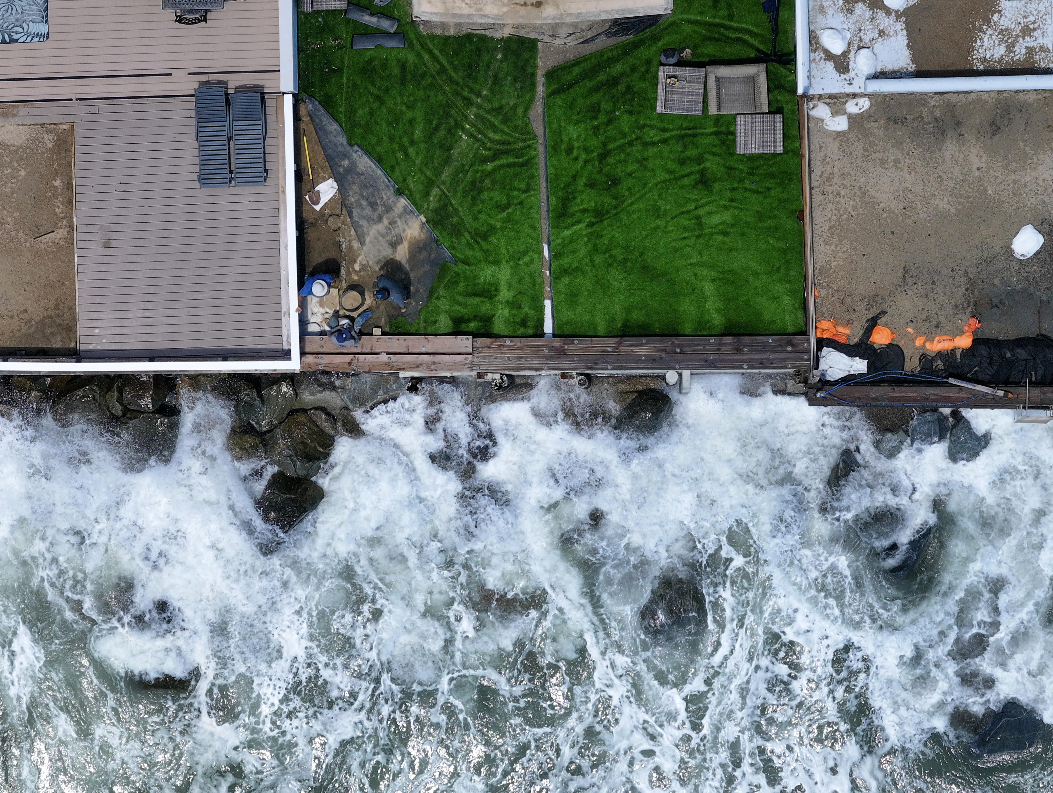Workers place sandbags at the corner of a patio as...