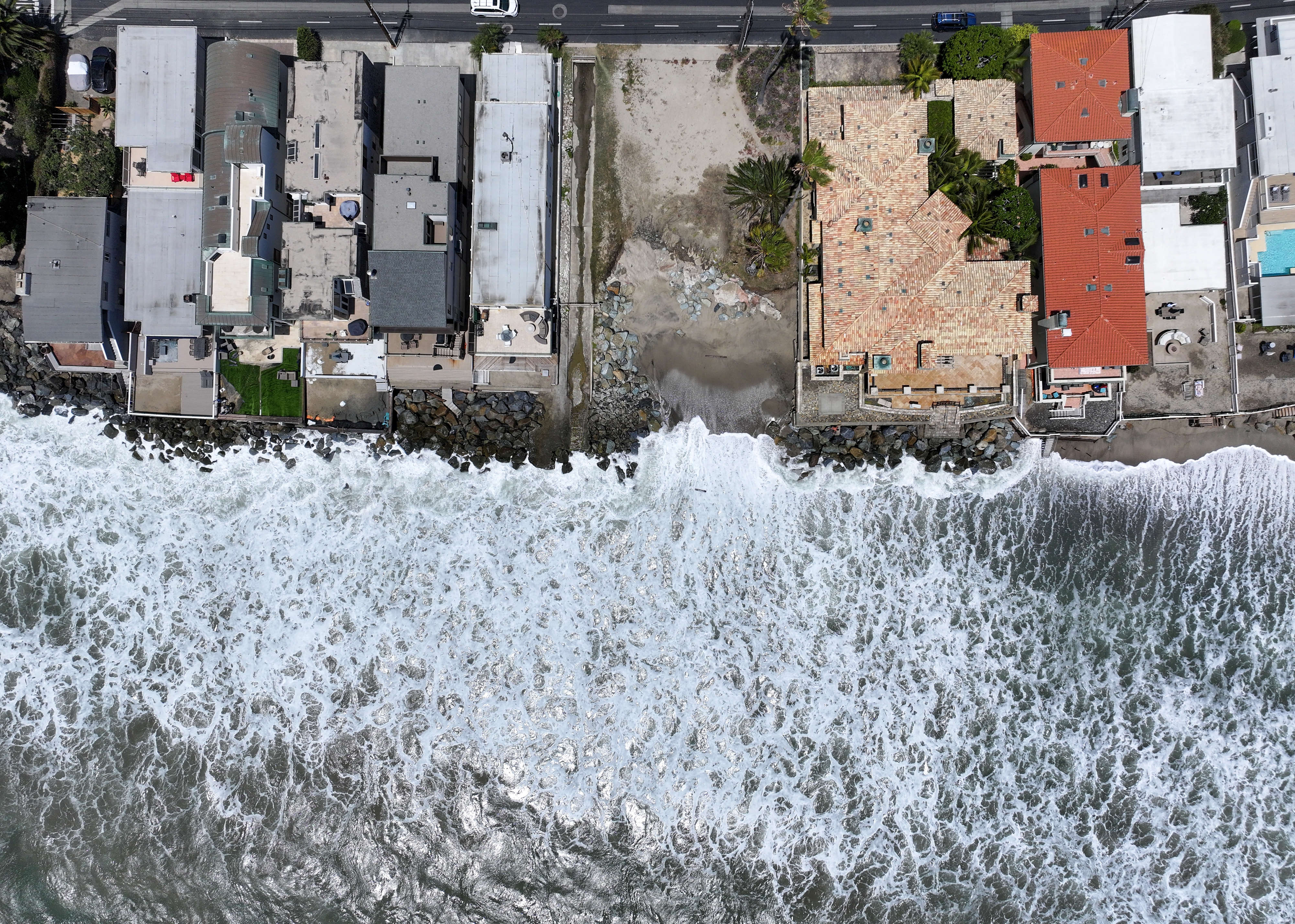 Waves hit the rocks below homes at Capistrano Beach in...