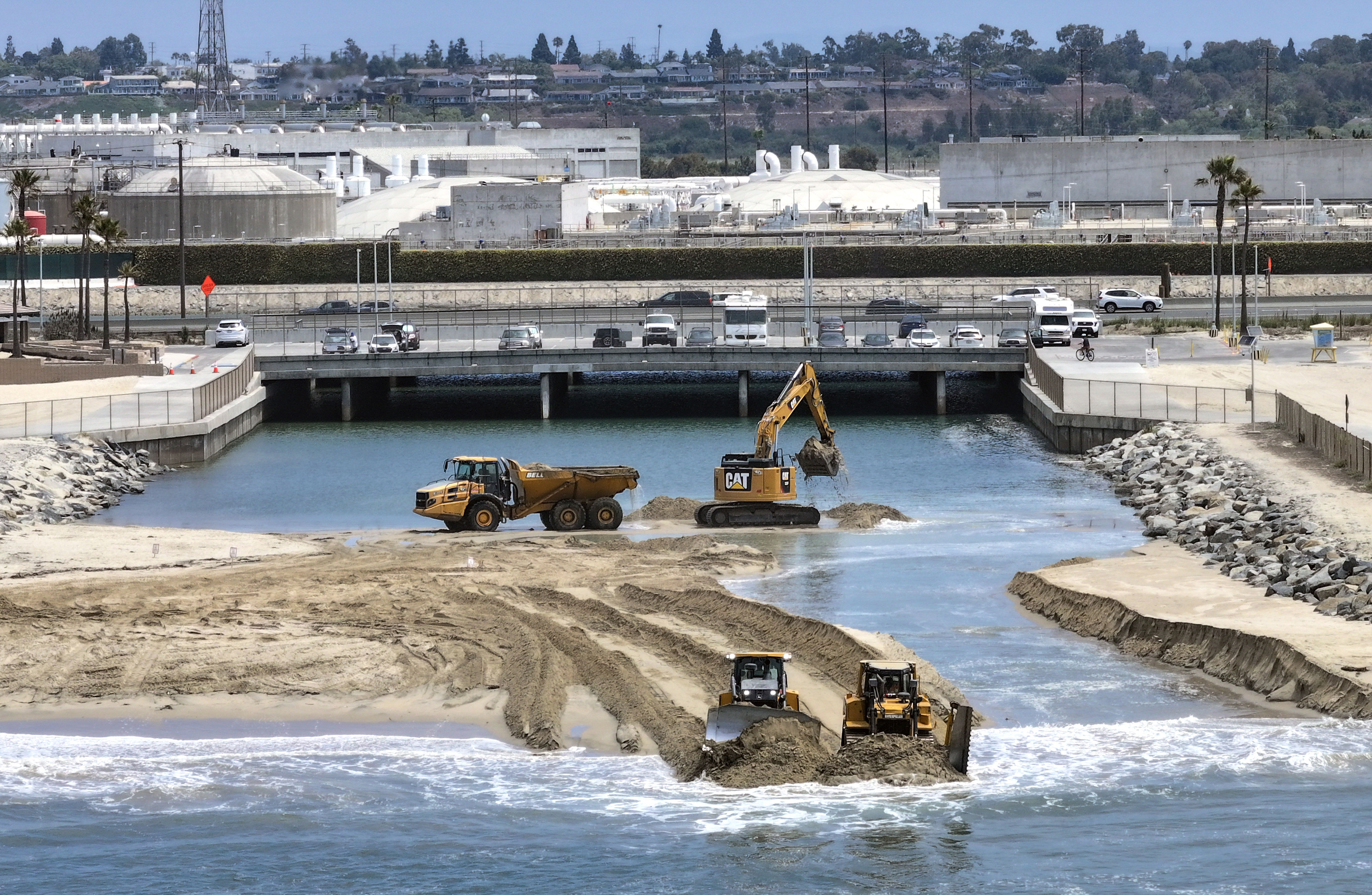 Workers clear sand from the opening between the Talbert Marsh...