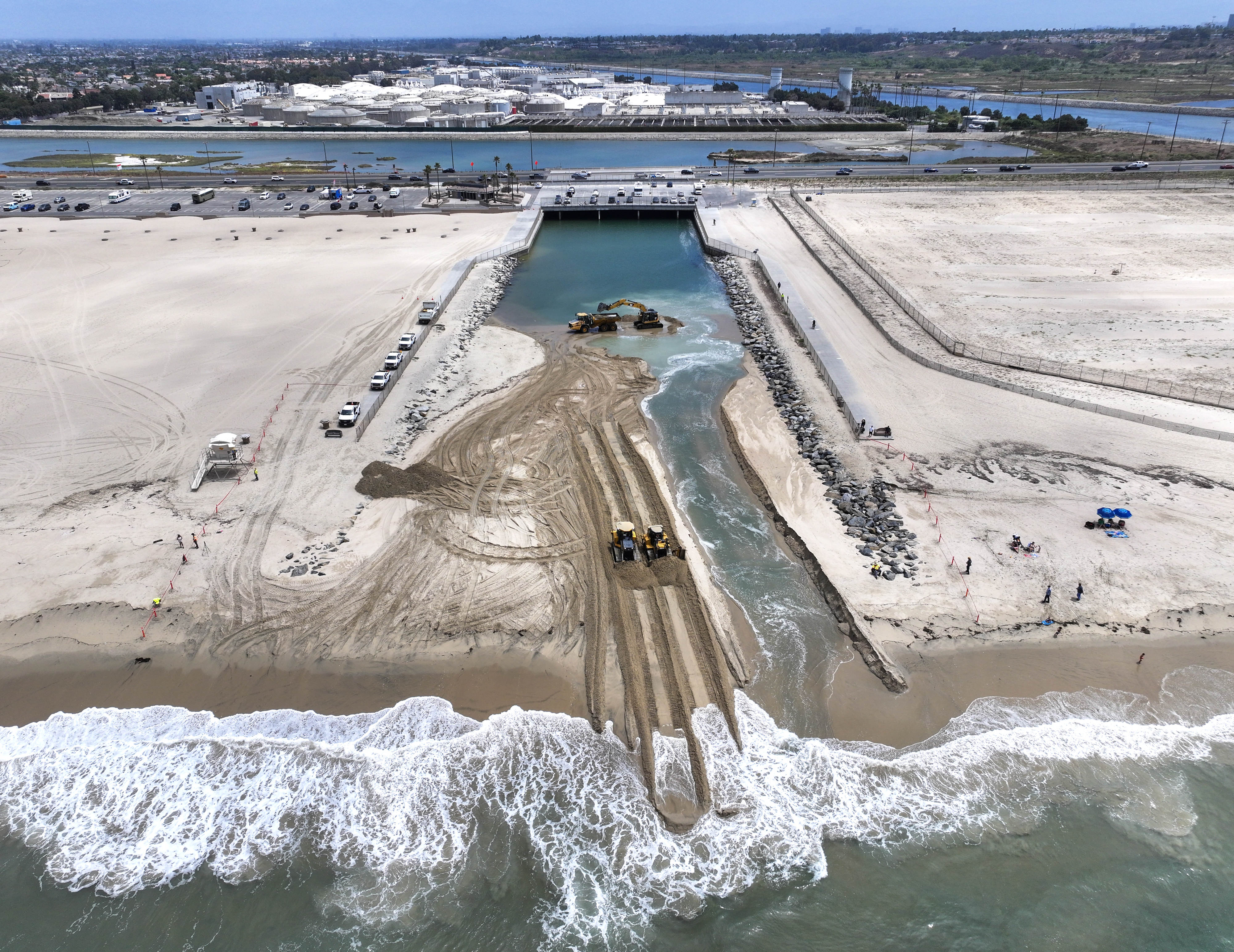 Workers clear sand from the opening between the Talbert Marsh...