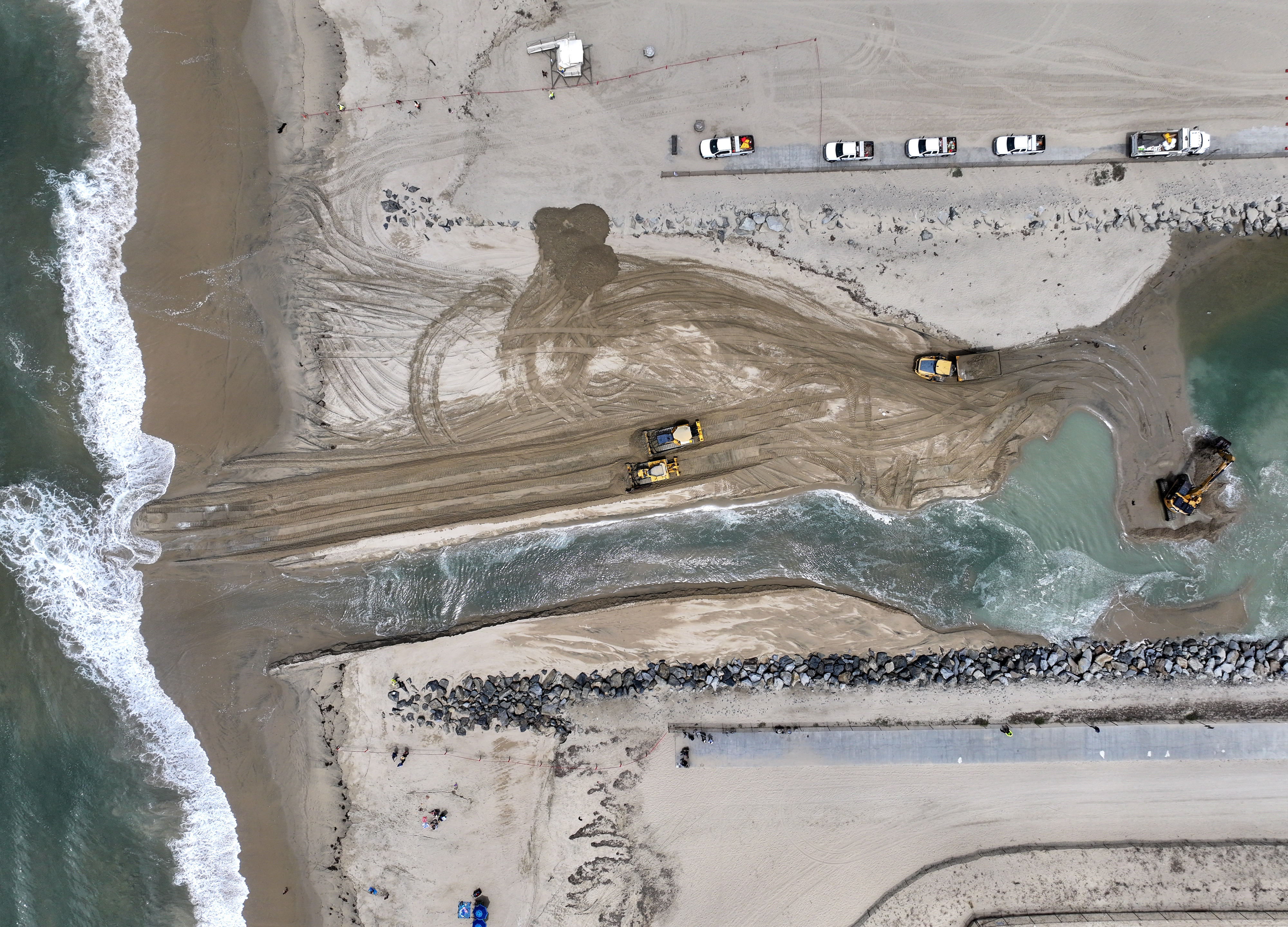 Workers clear sand from the opening between the Talbert Marsh...