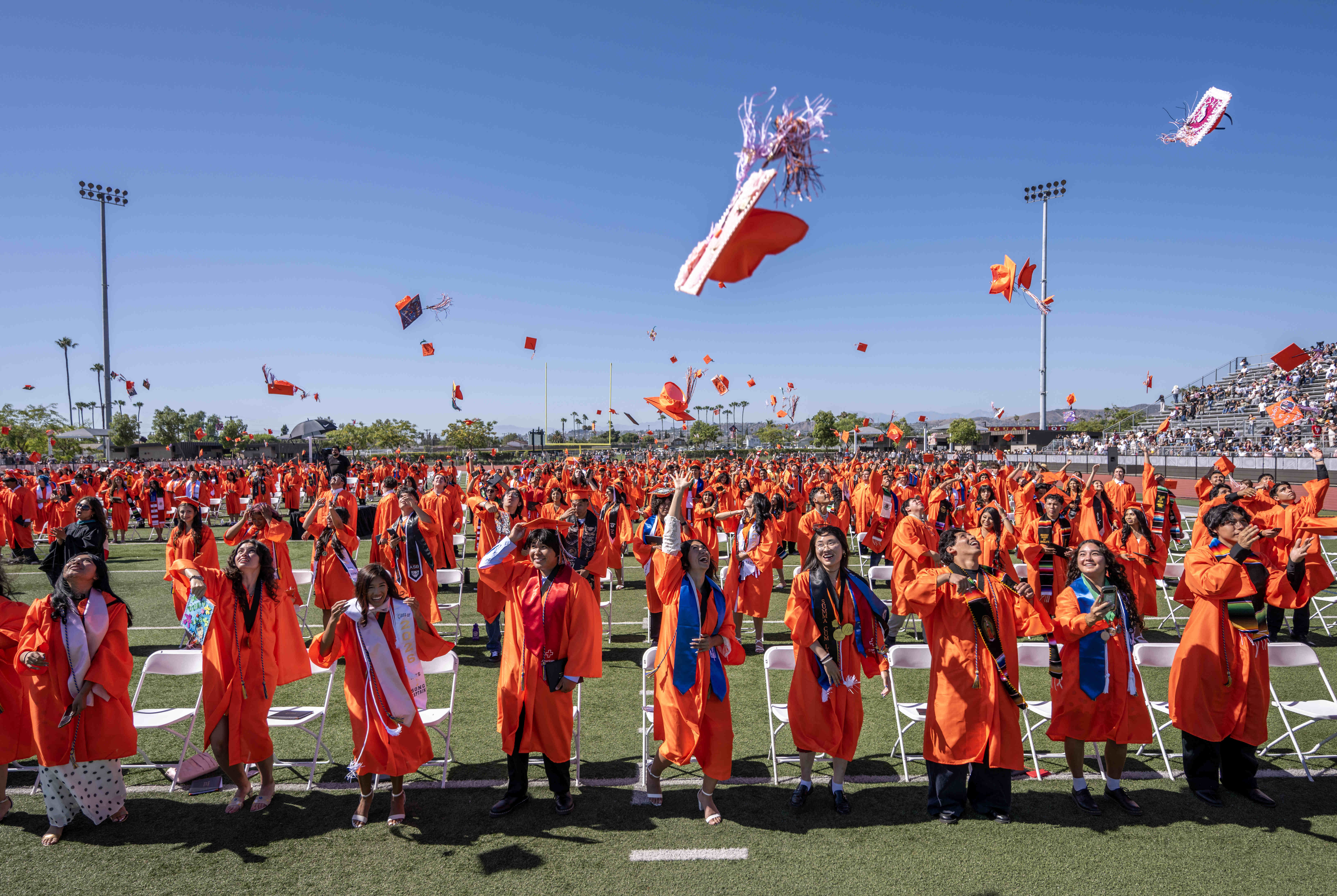 Orange High School graduates toss their caps in the air...