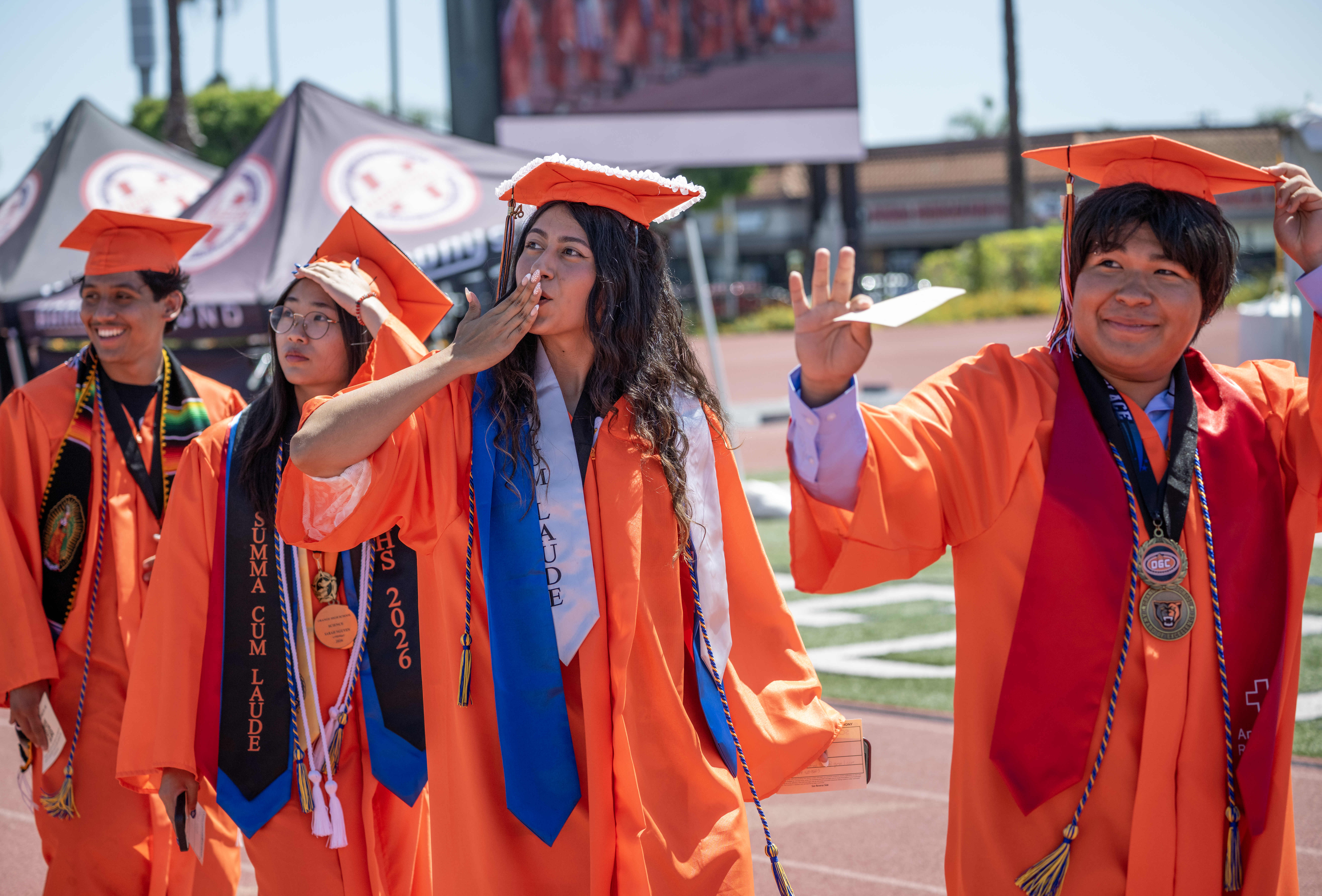 Graduates file into the stadium, acknowledging their loved ones in...