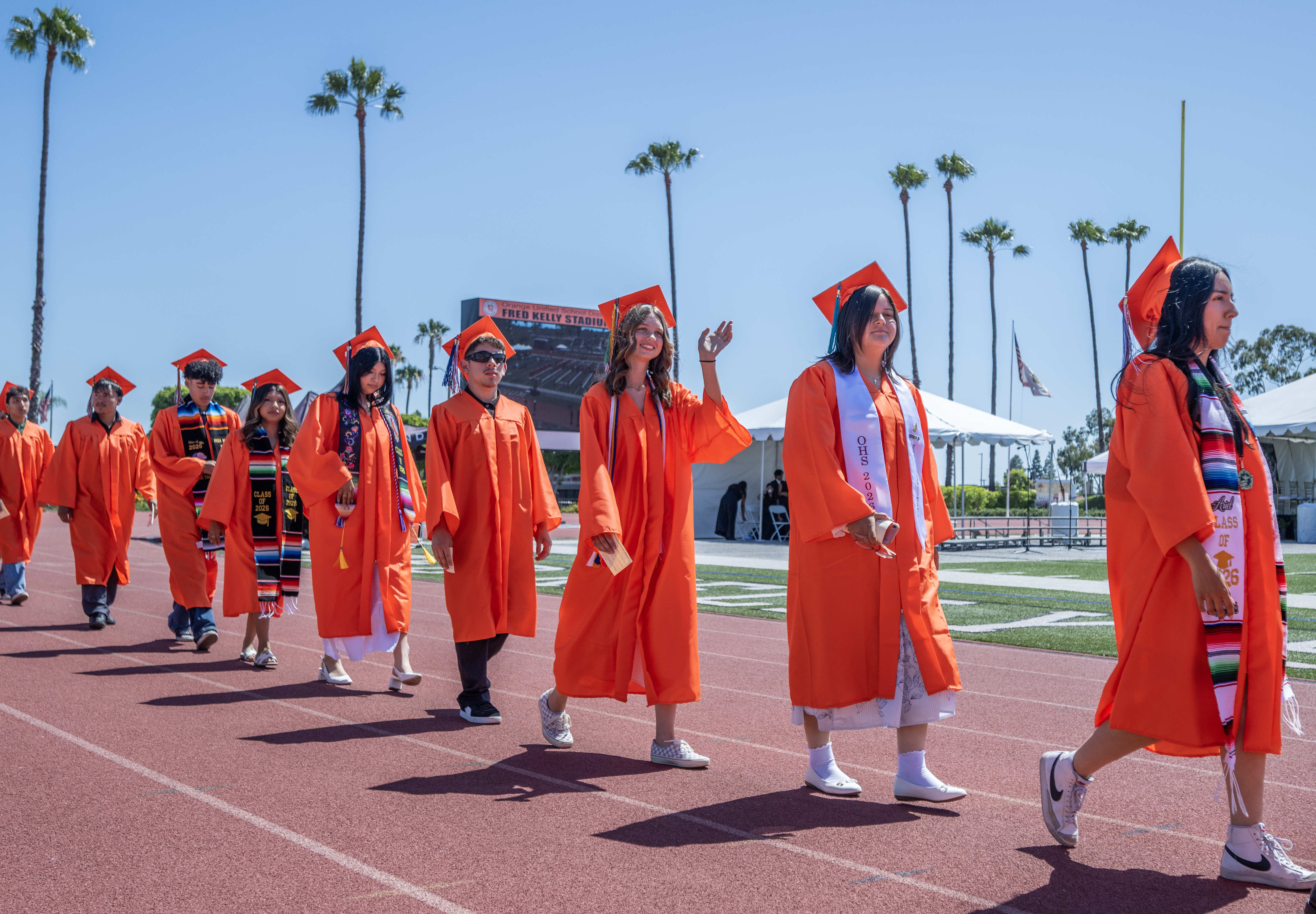 Graduates file into the stadium, acknowledging their loved ones in...