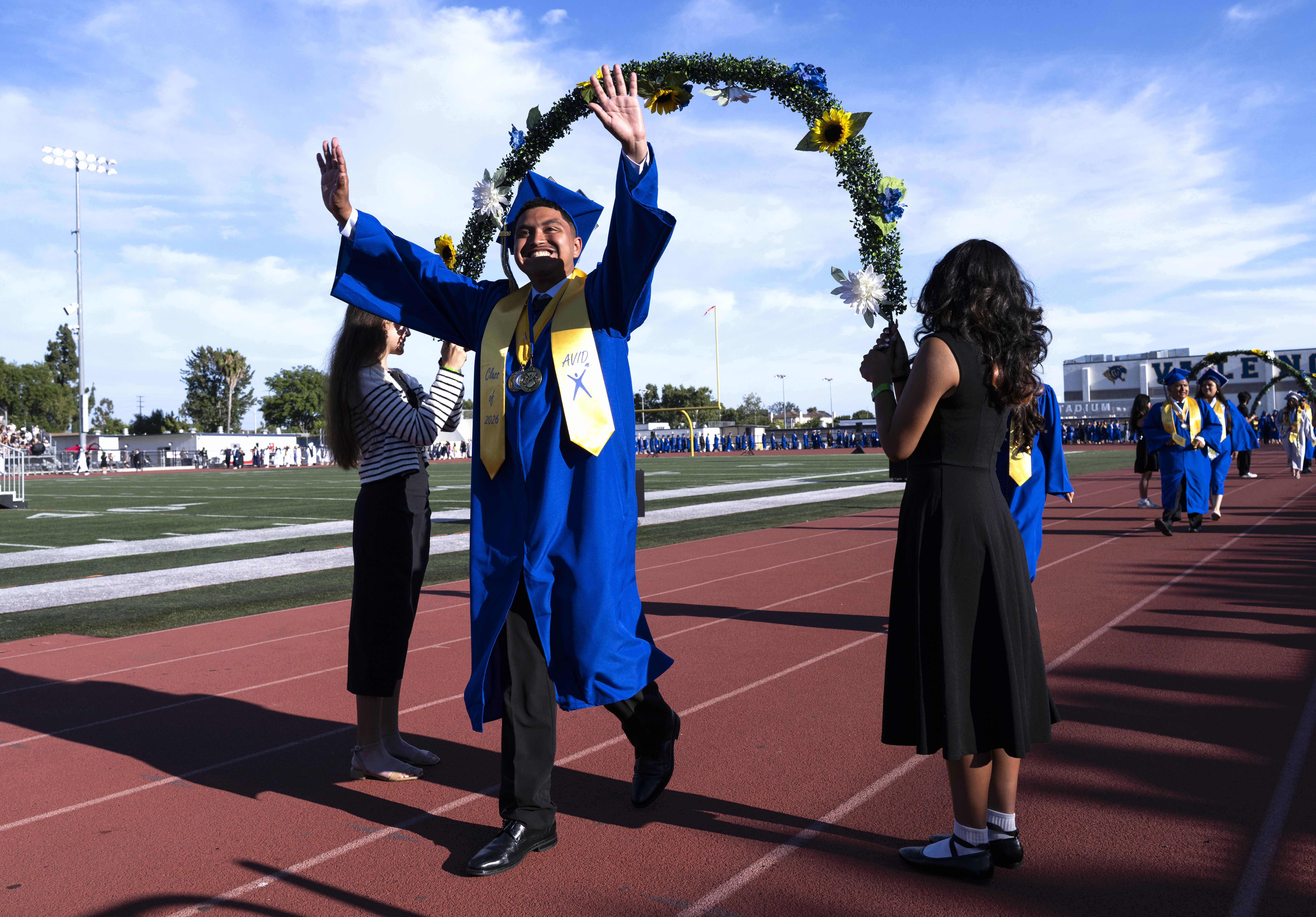 A graduate waves to the crowd in the stands in...