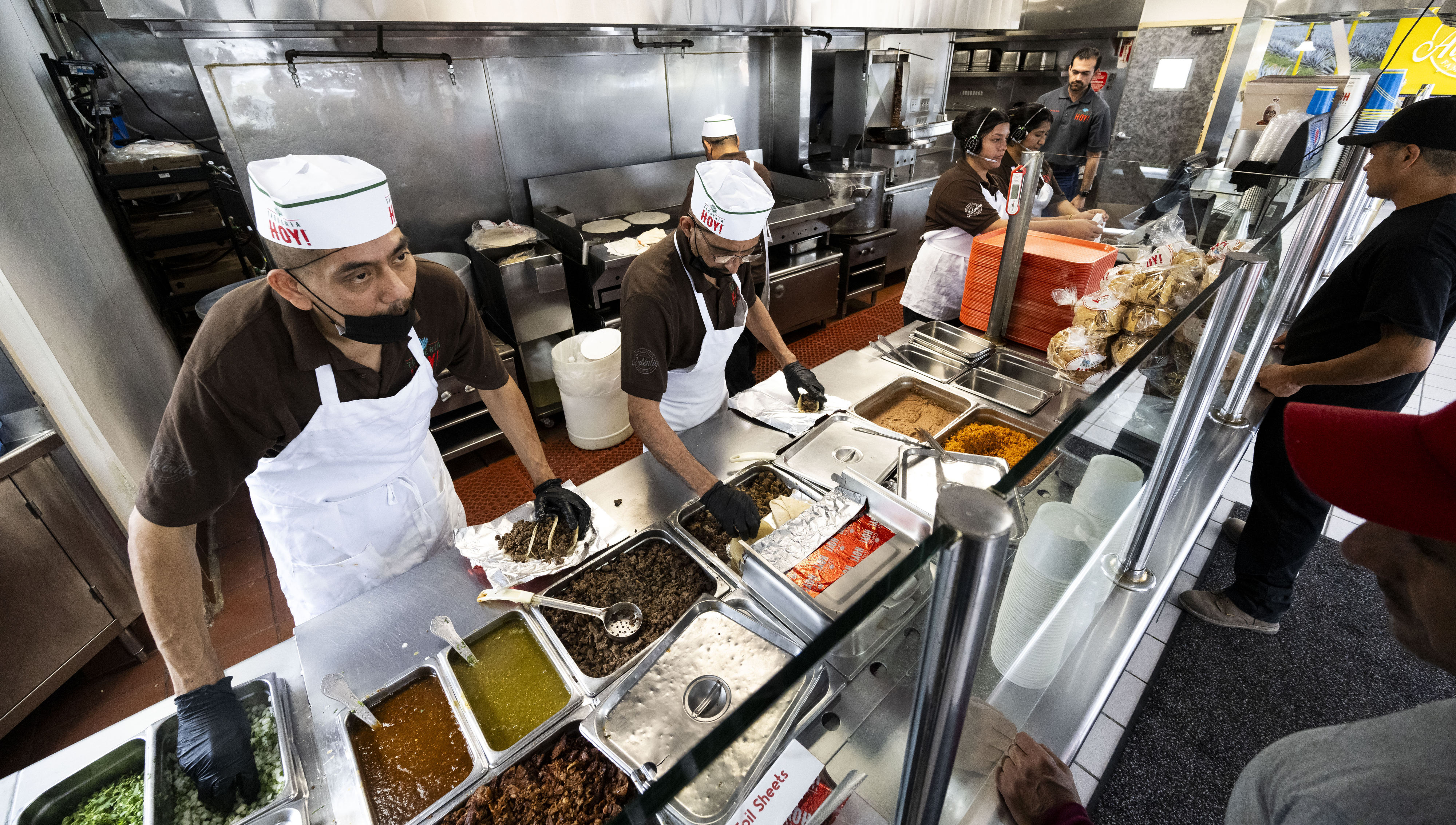 Workers take orders at Taqueria Hoy in Orange on Tuesday,...