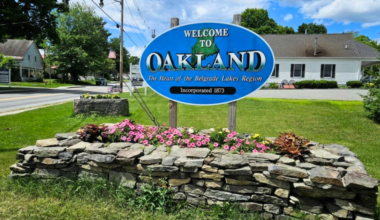 A sign is hung over a flower bed.