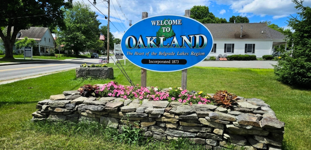 A sign is hung over a flower bed.