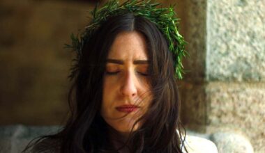 woman with long dark hair and crown of greenery, eyes closed in concentration