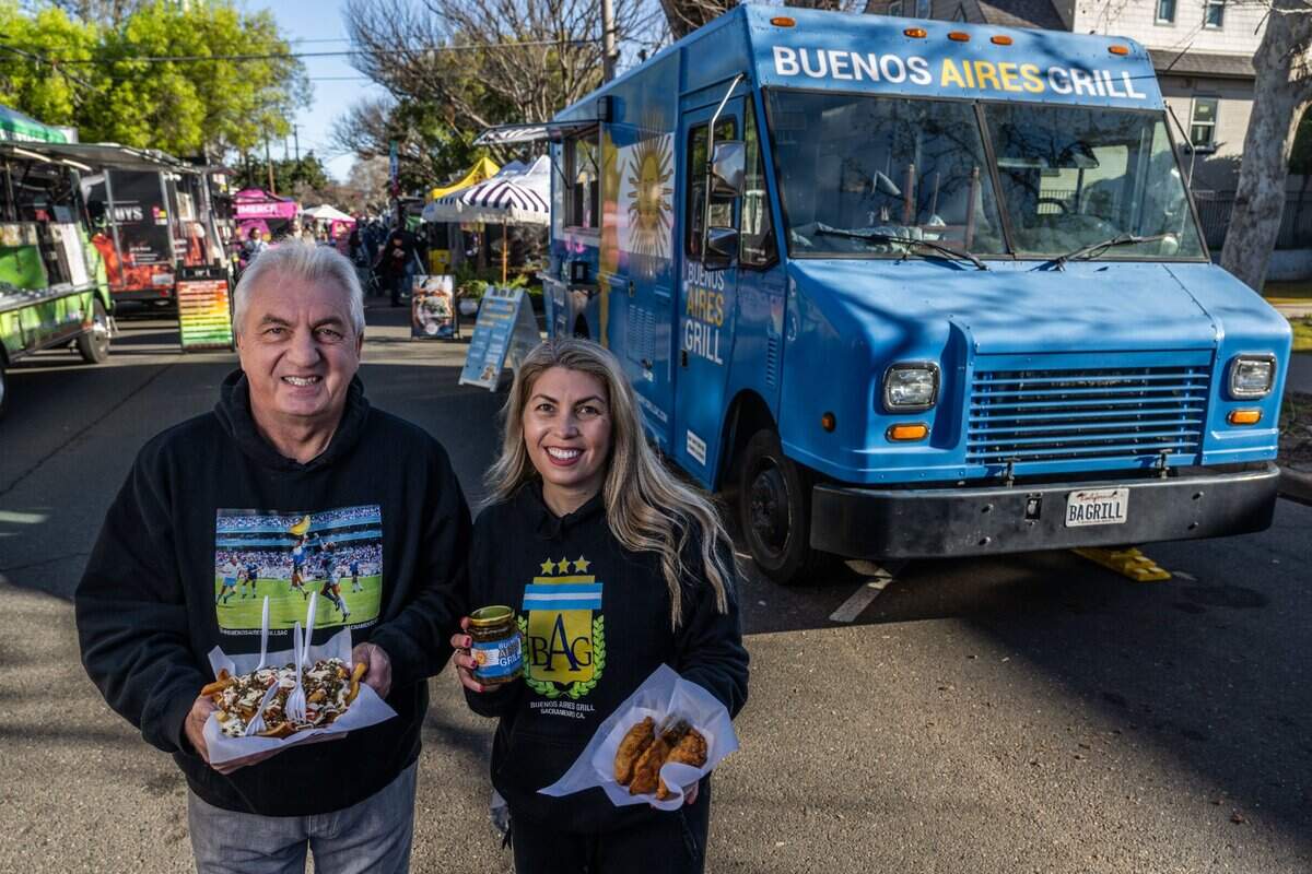 Ruben Bozzalla and his daughter Estefania Bozzalla hold some of the food they serve from their Buenos Aires Grill food truck on Saturday, Feb. 8, 2025 at the Midtown Farmers Market in Sacramento.  Ruben is holding their best-selling “messy” fries topped with chicken, mayonnaise and tomatoes and Estefania holds empanadas and a jar of chimichurri.