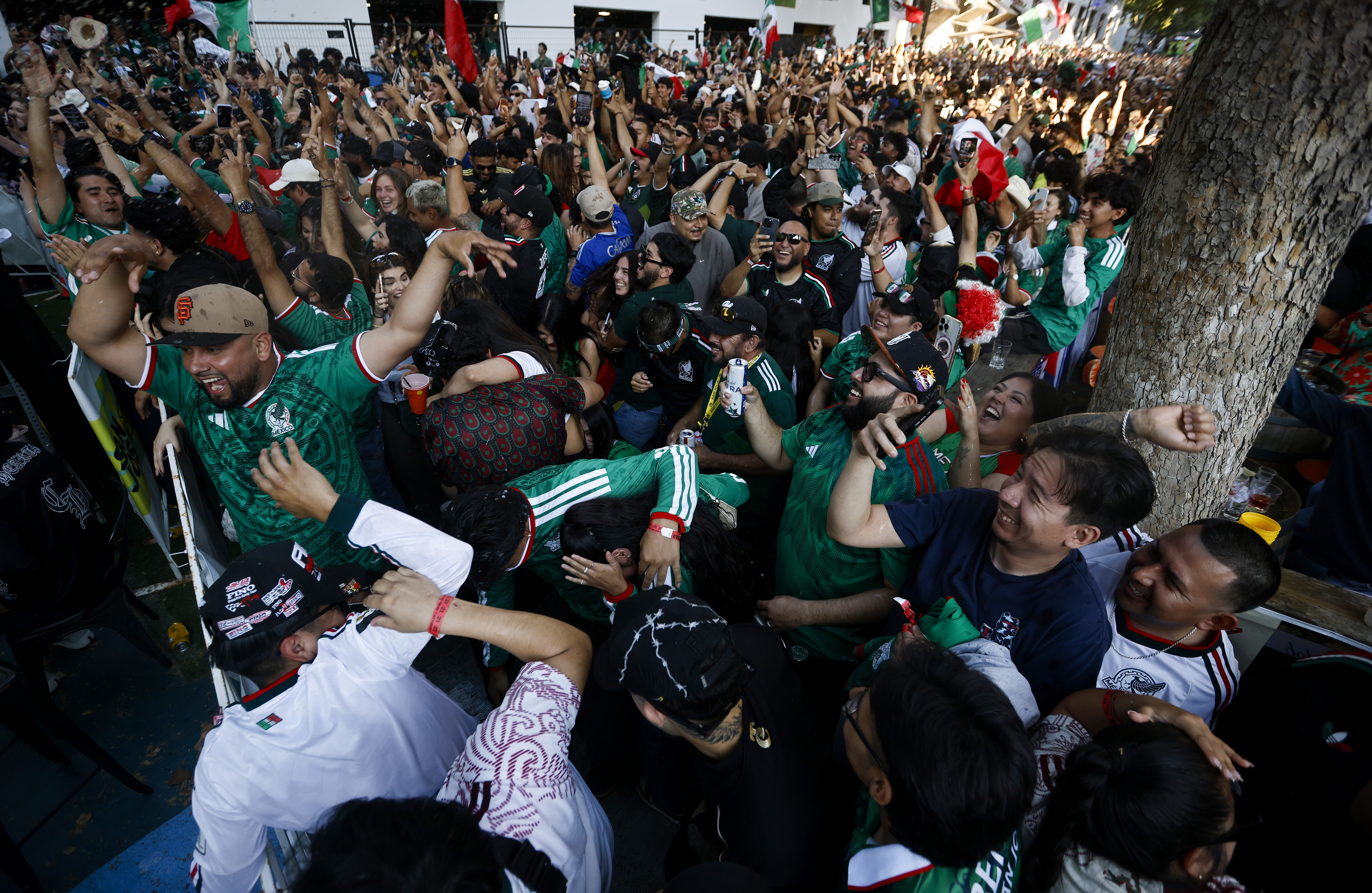 Soccer fans, mostly for Mexico, celebrate a goal by Mexico...