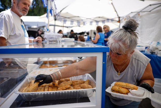 Kanella Dimulias, right, grabs a paximathia, a traditional Greek biscuit, for a customer at the San Jose Greek Festival at St. Nicholas Greek Orthodox Church in San Jose, Calif., on Sunday, May 31, 2026. (Nhat V. Meyer/Bay Area News Group)
