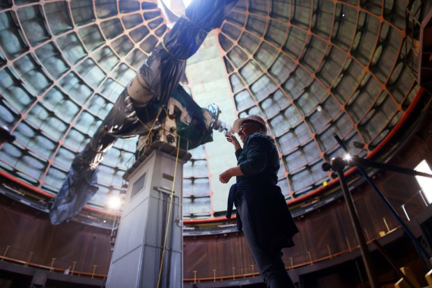 Lick Observatory astronomer Elinor Gates stands underneath a 36-inch Lick Refractor telescope covered in tarps on Monday, Dec. 29, 2025, in San Jose, Calif. A large metal shutter was torn off the dome during a recent wind storm. (Aric Crabb/Bay Area News Group)