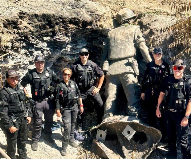 San Jose police officers stand in a steep embankment with the large bronze soldier statue after finding it June 21, 2026. The statue was hauled from the Vietnamese Heritage Garden about a mile away. (Courtesy of the San Jose Police Department)
