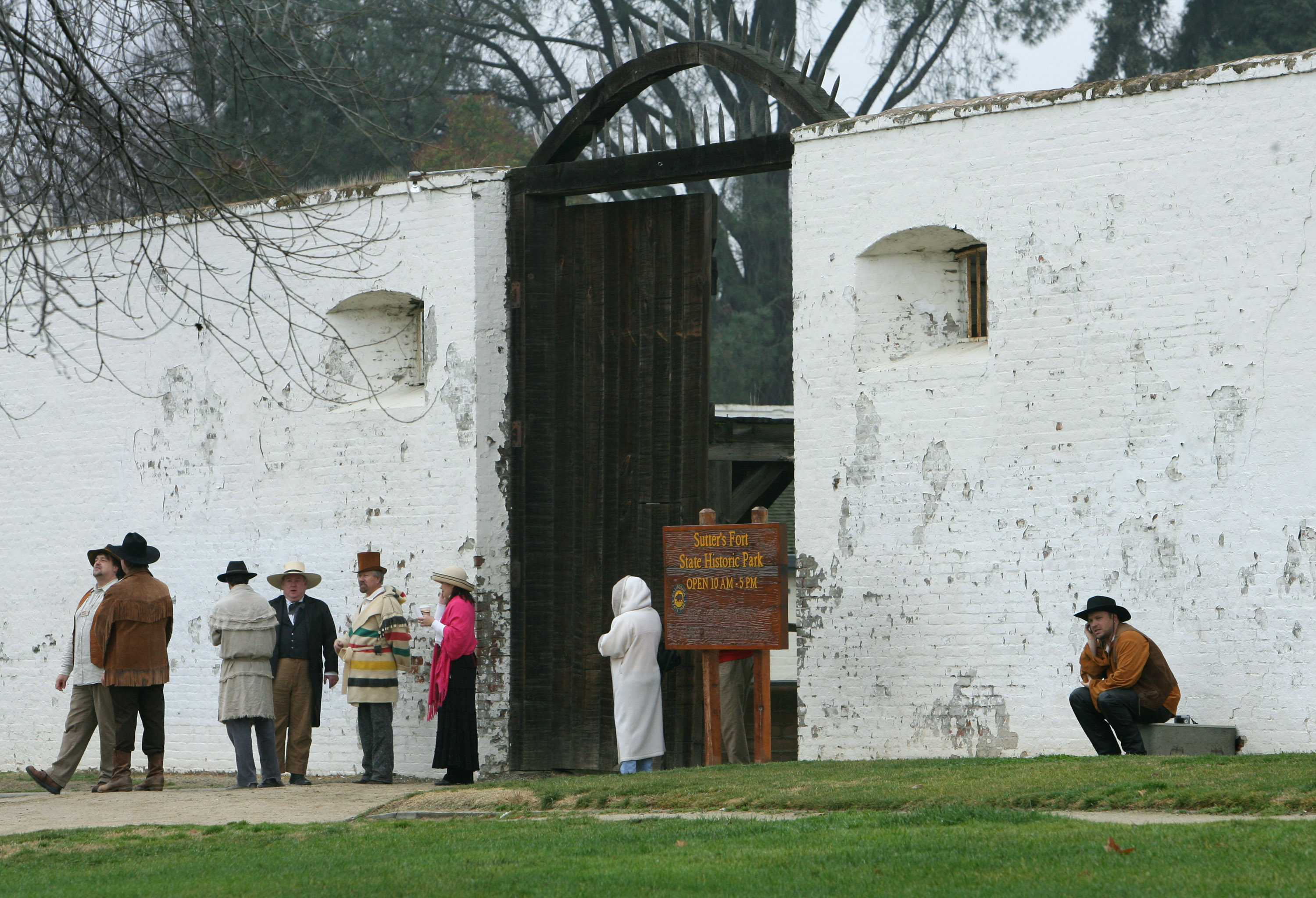 Docents dressed in period costumes wait for a group of...