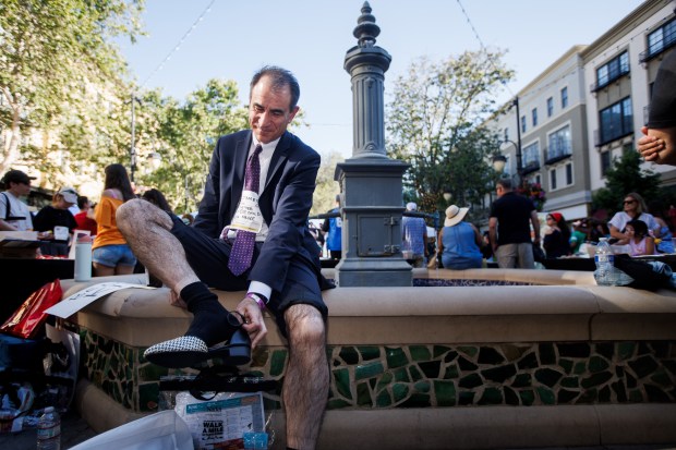 Santa Clara County Assistant District Attorney James Gibbons-Shapiro puts on a pair of pumps before marching at the annual Walk a Mile in Their Shoes event at Santana Row in San Jose, Calif., on Thursday, June 11, 2026. (Dai Sugano/Bay Area News Group)