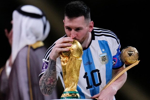Argentina's Lionel Messi kisses the World Cup trophy as he holds the the Golden Ball award for best player of the tournament, after the World Cup final soccer match between Argentina and France at the Lusail Stadium in Lusail, Qatar, Sunday, Dec.18, 2022. (AP Photo/Manu Fernandez)