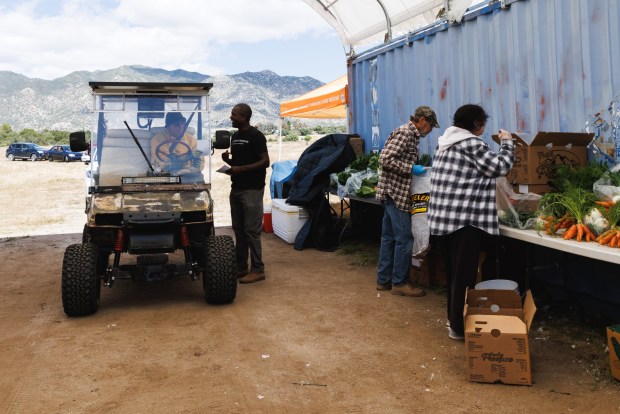 Farmer Byron Nkhoma, of Hukama Produce, speaks with Ranchita resident Miguel Estrima, 70, during a food distribution at a mobile pantry in Ranchita in April. Estrima said that as a disabled veteran, he appreciates programs like this. (Kristian Carreon / The San Diego Union-Tribune)