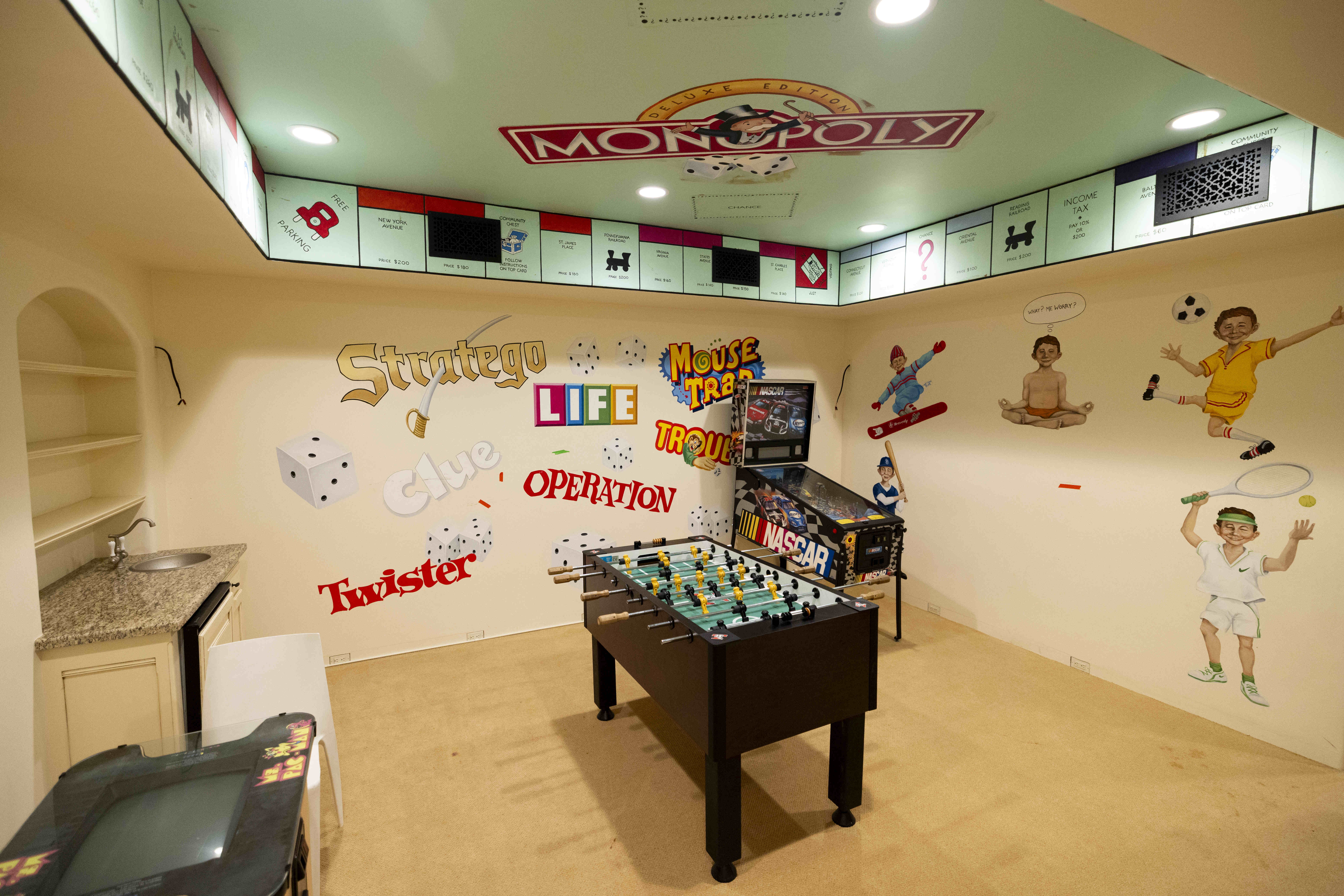 A game room, with a Monopoly board on the ceiling,...