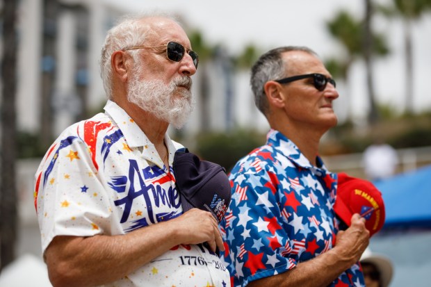 Michael Boody, 75, and Mike Frazier, 63, stand for the national anthem during the USA 250 festival in Oceanside on Saturday, June 27, 2026. (Kristian Carreon / The San Diego Union-Tribune)