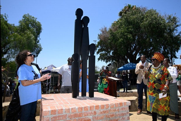 Lynn Brown, left, and Makeda Cheatom watch as the restored Black Family Statue designed by artist Rossie S. Wade is unveiled at Neal Petties Mountain View Community Park June 13, 2026 in San Diego, Calif. (Denis Poroy / For The San Diego Union-Tribune)