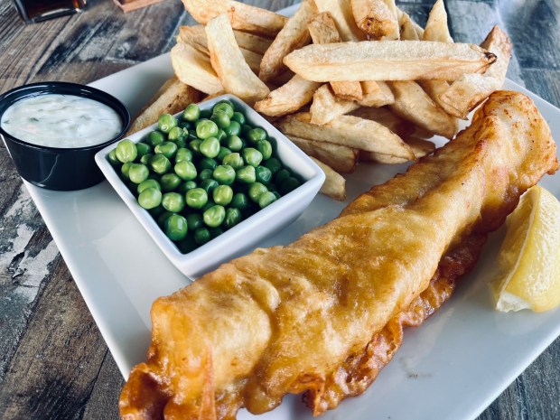 Beer-battered fish and chips is served with peas or coleslaw at Shakespeare Pub & Grille. (Carlos Rico / The San Diego Union-Tribune)