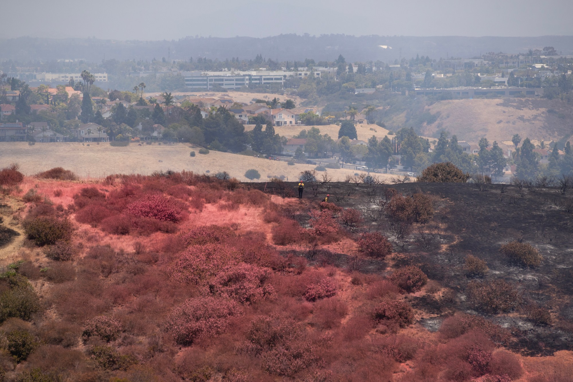 San Diego, CA – Fire retardant covers the ground as...