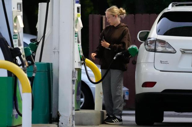 A customer checks gas price before she fills up her vehicle's tank.