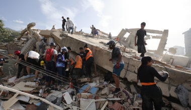 Rescue workers and civilians search through the rubble of a collapsed building following an earthquake in Venezuela.