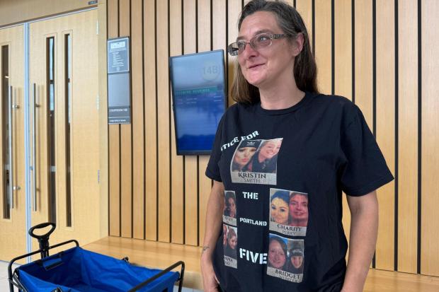 Diana Allen wears a shirt showing five women, including her daughter, Charity Perry, whom Jesse Calhoun is accused of murdering, after Calhoun was arraigned on a fifth second-degree murder charge, in Portland, Ore. on Wednesday, June 3, 2026. (AP Photo/Claire Rush)
