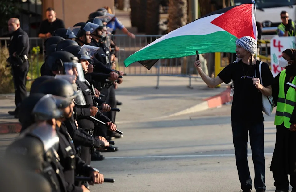 A pro-Palestinian protestor walks along a line of LAPD officers outside Pomona College’s commencement ceremony. Getty Images