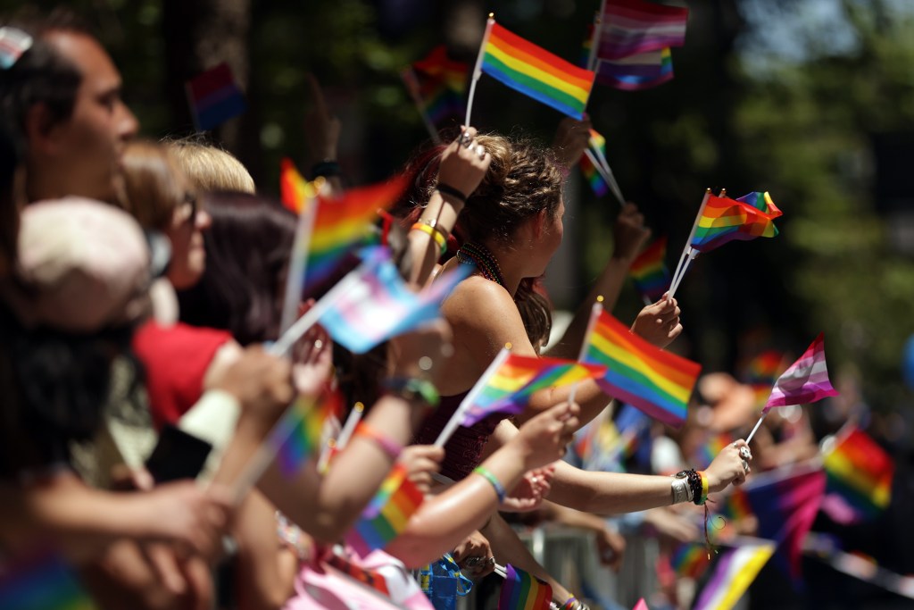 Attendees waving pride flags at a parade.