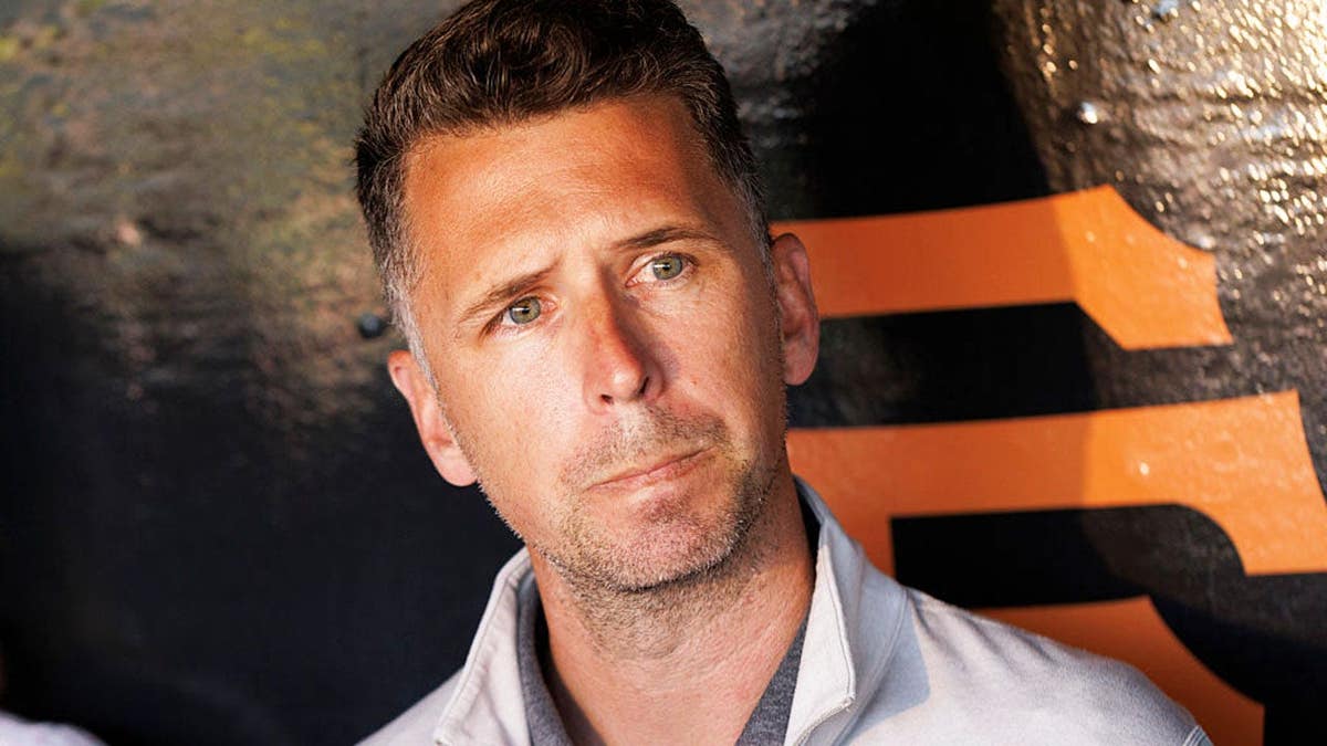 Buster Posey speaking at a microphone at Oracle Park in San Francisco