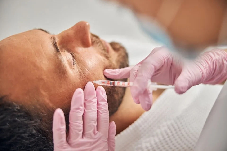 A man receiving an injectable skincare treatment from a cosmetologist. Svitlana – stock.adobe.com