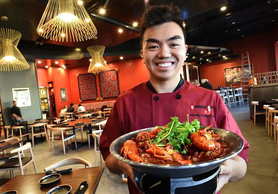 Jason Lin holds a platter of hot and spicy crawfish at his new Spicy J’s Specialty Chinese Cuisine in River Park in this file photo from 2019.