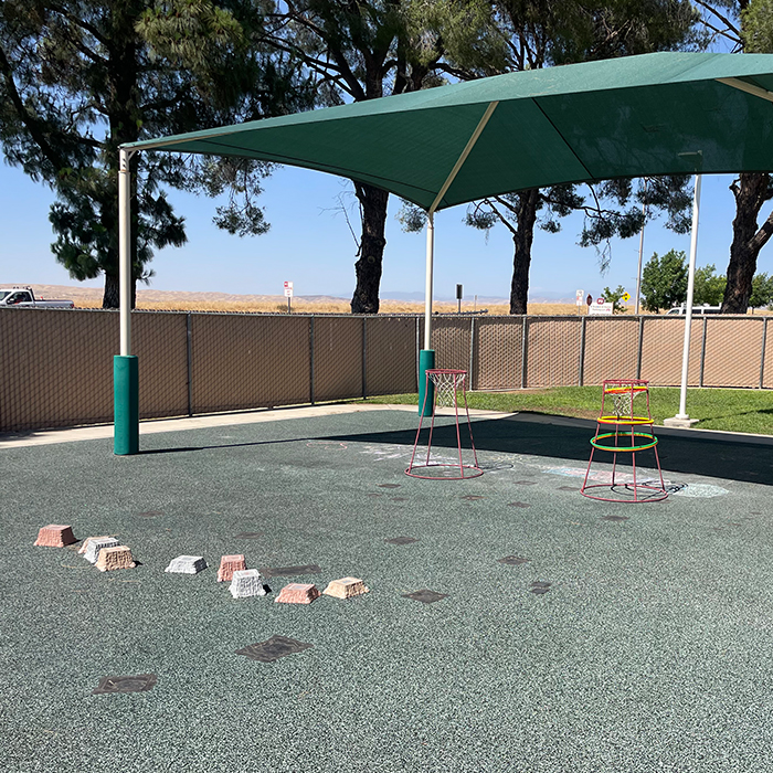 Outdoor area with a small basketball hoop and large tent for shade