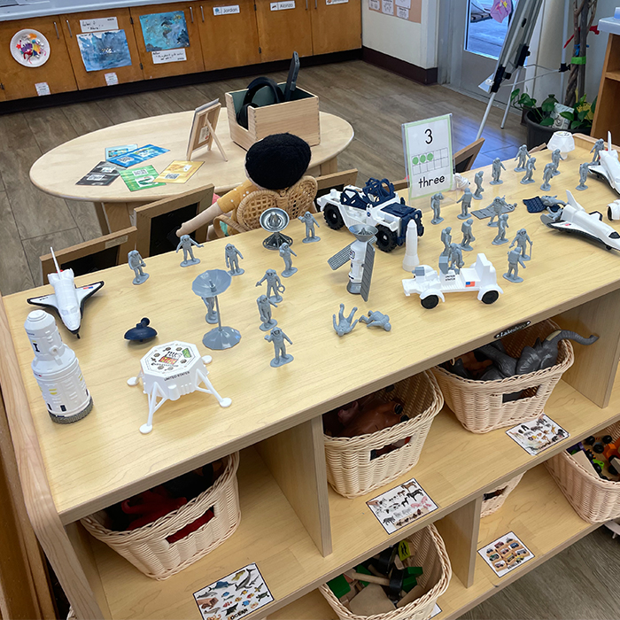 classroom shelf with several space themed toys sitting on top of it