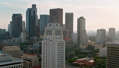 Aerial shot of Los Angeles City Hall in Downtown Los Angeles with financial district skyscrapers in background at sunset.