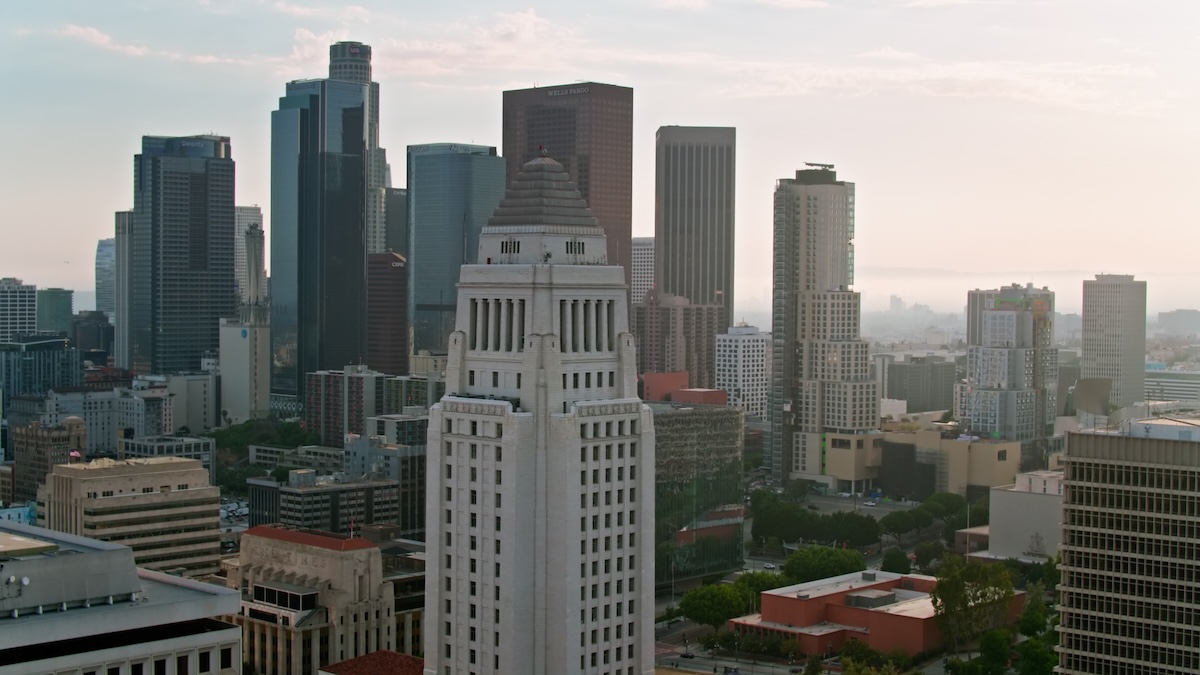 Aerial shot of Los Angeles City Hall in Downtown Los Angeles with financial district skyscrapers in background at sunset.