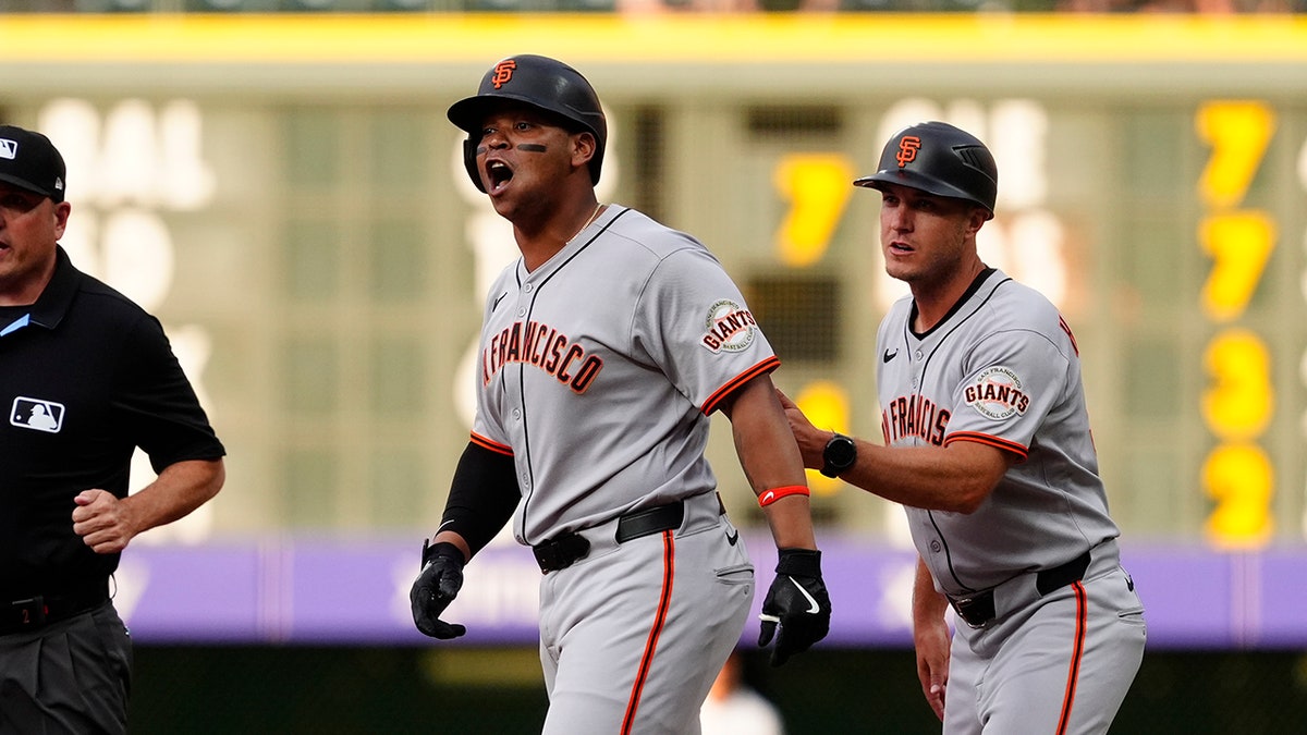San Francisco Giants third baseman Rafael Devers reacting near first base coach Mark Hallberg at Coors Field.