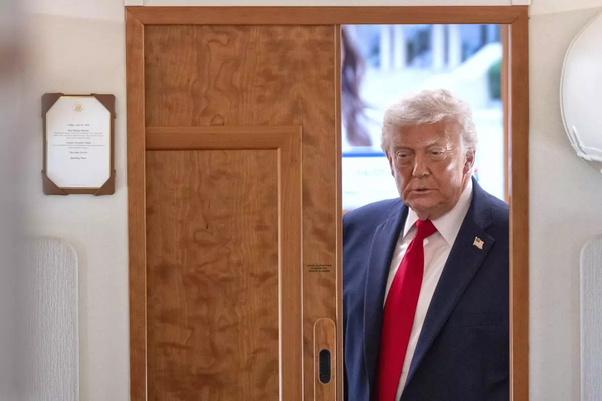 President Donald Trump arrives to speak to reporters aboard Air Force One en route from Joint Base Andrews, Md., to Eau Claire, Wis., Friday, June 5, 2026. (AP Photo/Mark Schiefelbein)