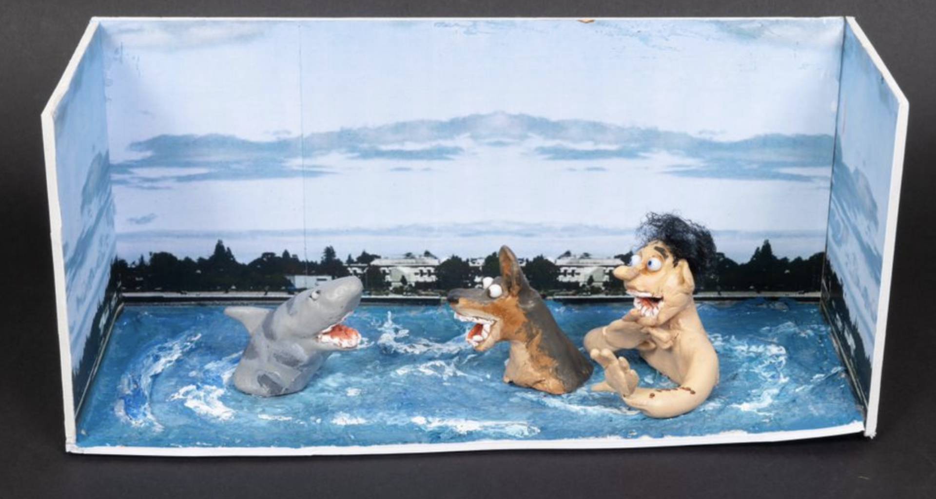 A model featuring a white boy and his dog, chest-deep in the ocean, facing off against a cartoonish-looking shark.