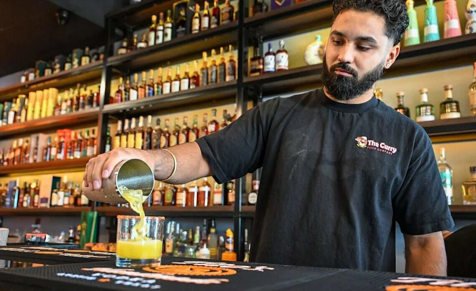 Bartender Navi Singh fills a glass with a Sunnyside Spice specialty cocktail at The Curry Pizza Company's newest location on Fowler south of Belmont in southeast Fresno on Tuesday, June 9, 2026. This one has a full bar.