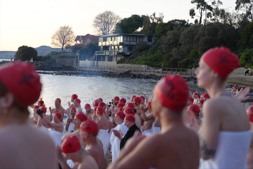 Crowd of swimmers prepare to enter the water for Dark Mofo's 2026 Nude Solstice Swim