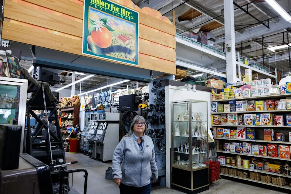 Pam Elyea, Vice President of History For Hire prop house, standing amidst shelves of various props. Jonathan Alcorn for CA Post